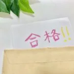 封筒からはみ出す合格通知と緑の葉。合格に歓喜する瞬間を表現。