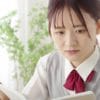 教室で熱心に勉強する女子学生。集中して本を読みながらノートを取る姿が印象的です。