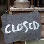黒板に白字で「CLOSED」と書かれた看板が店の扉にぶら下がっている。
