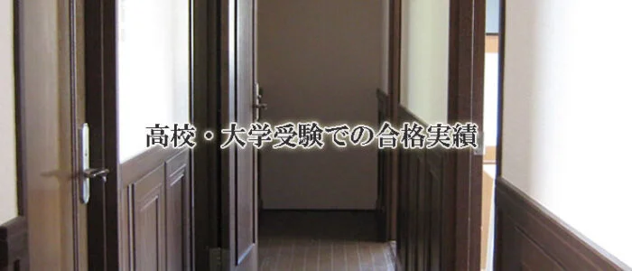 木製のドアと羽目板のある廊下の突き当たりには開いたドアがあります。中央には「高校・大学受験での合格実績」と書かれた日本語があり、鎌倉市の塾の室内の様子を写しています。