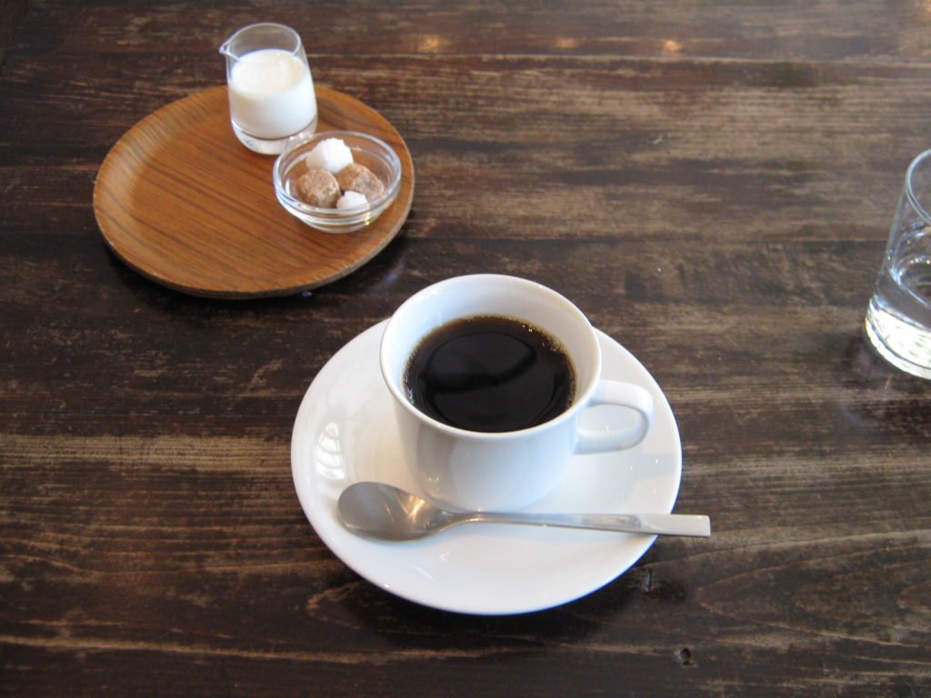 居心地の良いカフェでテーブルにはコーヒーが置かれている。cozy/cosyという英単語の意味を説明する視覚資料。